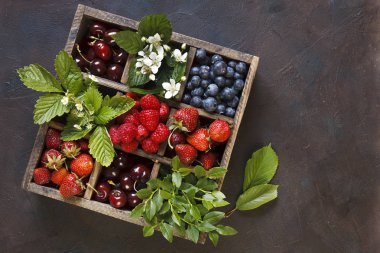 yakın çekim fotoğraf taze çilek yeşil yaprakları ile ahşap kutusunda siyah tablo arka plan üzerinde ayarlayın.