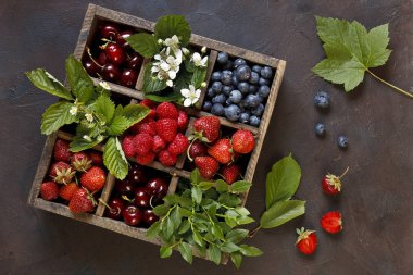 yakın çekim fotoğraf taze çilek yeşil yaprakları ile ahşap kutusunda siyah tablo arka plan üzerinde ayarlayın.
