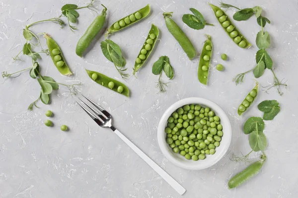 Pods of green peas and pea on grey background, top view