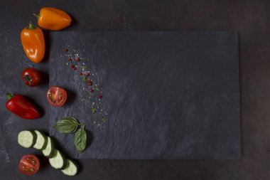 Close-up photo of fresh vegetables on black stone cutting board. Top view  on dark concreted table background clipart