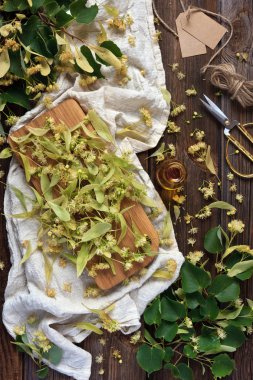  Ihlamur çiçek ve güzel kokulu bir cam şişe özünde. Bitkisel ilaç, spa ve sauna için aksesuarlar. Antika ahşap rustik arka plan üzerinde üstten görünüm.