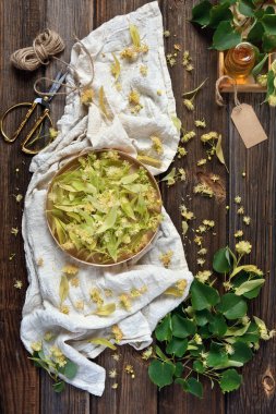 Ihlamur çiçek ve güzel kokulu bir cam şişe özünde. Bitkisel ilaç, spa ve sauna için aksesuarlar. Antika ahşap rustik arka plan üzerinde üstten görünüm.