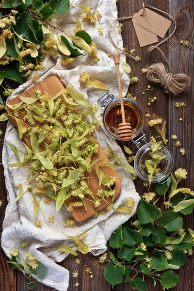  Ihlamur çiçek ve şeffaf cam kavanozda doğal bal. Bitkisel ilaç, spa ve sauna için aksesuarlar. Antika ahşap rustik arka plan üzerinde üstten görünüm.