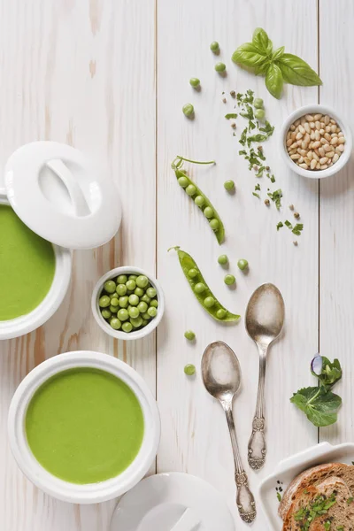 Ev yapımı taze yeşil bezelye krem çorba baharatlar, çam fıstığı ve tost ciabatta ekmeği. Beyaz ahşap zemin üzerinde yukarıdan görmek