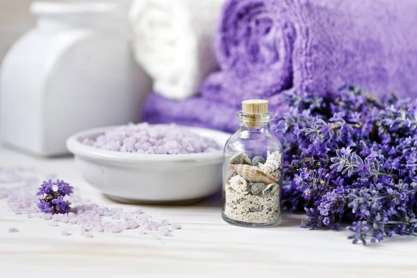 Lavanta çiçekleri, aromatik deniz tuzu ve havlular. Kaplıca, güzellik salonu ve sağlık salonu, kozmetik mağazası. Beyaz ahşap arka plandaki resmi kapat.