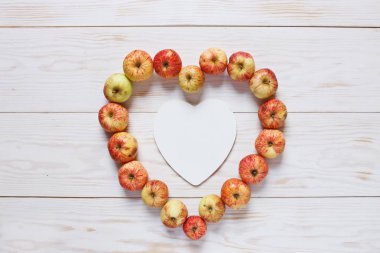 Beyaz ahşap arka plan, üstten görünüm üzerinde boş kart ile kalp şeklinde taze sulu elma 