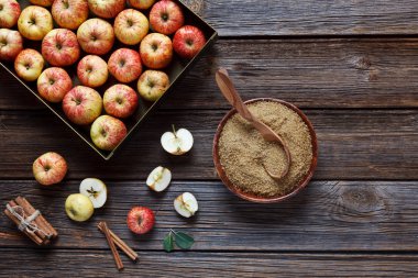 Metal kutu, kahverengi şeker ve tarçın ahşap arka plan üzerinde taze sulu elma