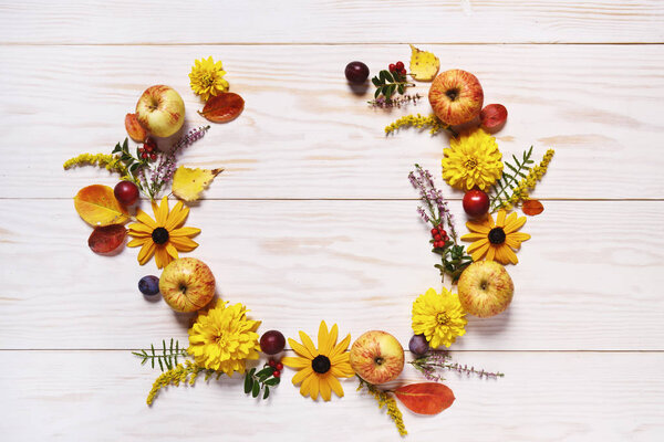 Apples, plums, red berries and beautiful flowers on white wooden background. Top view with copy space.  