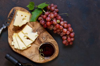 Kırmızı üzüm ve peynirle vintage koyu arka plan, üstten görünüm, yakın çekim ahşap kesme tahtası üzerinde kırmızı şarap şişe