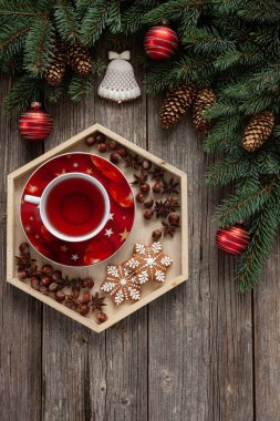 köknar ağacı dalları, koniler, Noel süsleri ve kırmızı çay ile gingerbread kar taneleri üzerinde ahşap masa, üstten görünüm