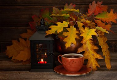 Sarı yapraklar, fener ve sıcak kahve fincanı kopya alanı ile ahşap arka plan üzerinde sıcak sonbahar arka plan