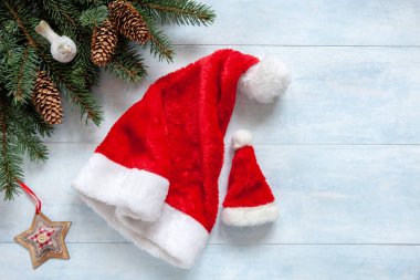 Köknar ağacı dalları, şakrak kuşu, koniler, Noel yıldızı ve büyük ve küçük iki Santa şapka Noel arka plan.