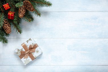Noel köknar ağacı dalları, koni ve hediye kutusu arka plan. Noel ve yeni yıl kavramı. Yakın çekim, en iyi görünümü üzerinde ışık mavi ahşap masa, sizin metin için yer 