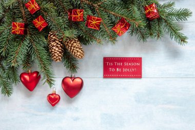Christmas  background with fir tree branches, cones and Christmas heart shape decorations. Christmas and New Year concept. Close-up, top view on light blue wooden table, place for your text 
