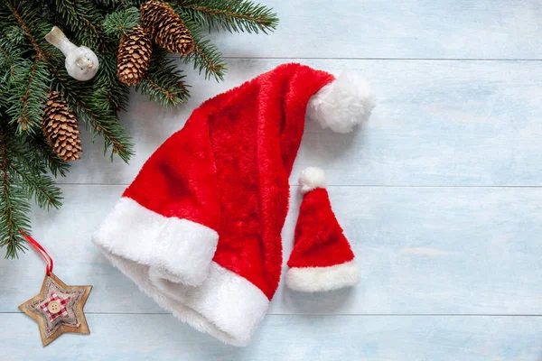 圣诞节背景与冷杉树分支 Bullfinch 圣诞节星并且二个圣诞老人帽子大和小 — 图库照片
