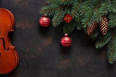 Eski keman ve köknar ağacı dalları ile Noel topları ve koniler karanlık beton zemin üzerine