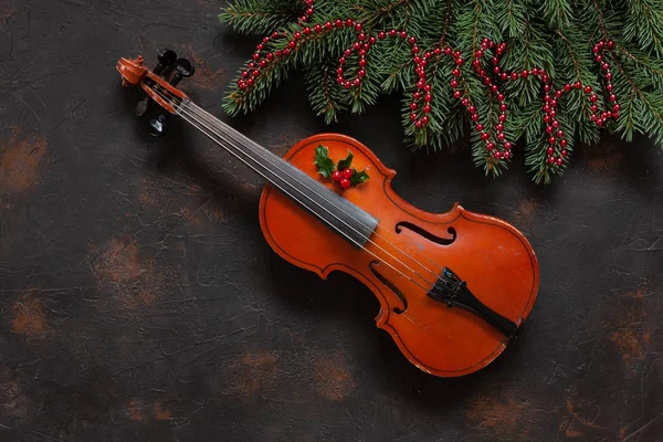 Eski keman ve köknar ağacı dalları ile Noel dekor karanlık beton zemin üzerine