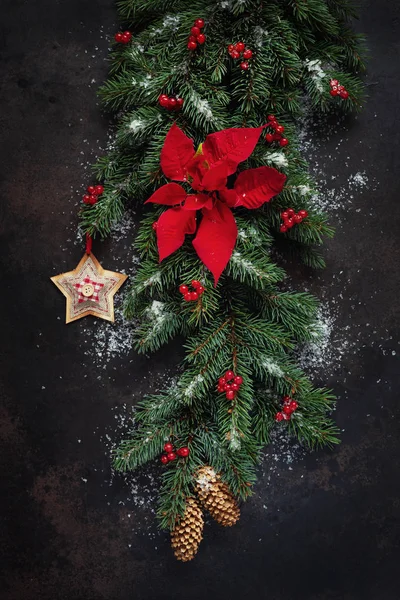 クリスマスの休日の背景にモミの木の枝 暗い背景にポインセチアと赤果実とコーン 上面ビュー クリスマスと新年のコンセプト — ストック写真
