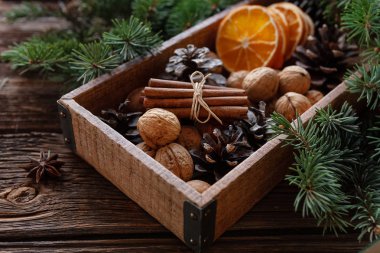 Ceviz, fındık, koniler, portakal rustik ahşap arka plan köknar ağaç dalları ve Noel ışıkları ile ahşap kutusunda. Yakın, seçici odak