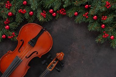 Old violin and fir-tree branches with Christmas decor.  Christmas and New Year's concept. Top view, close-up on dark concrete background