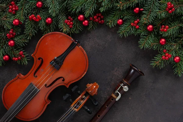 Eski keman ve flüt köknar ağacı dalları ile Noel dekorasyonu ile. Noel ve yeni yıl kavramı. Üstten görünüm, karanlık beton arka plan üzerinde yakın çekim
