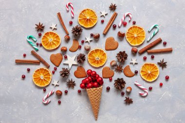 Christmas creativity concept with red balls,  candy canes, cookies, spices, dry orange slices in the waffle.  Flat lay, Close-up, top view on light  wooden table, place for your text clipart
