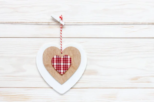Wooden colorful heart on rope. Concept for Valentine\'s Day, wedding, engagement and other romantic events. Top view, close-up, flat lay on white wooden background
