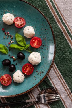 Beyaz mozzarella topu peynir, kırmızı kiraz domates, zeytin ve fesleğen Close-up. Üstten görünüm, düz yatıyordu