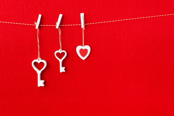 Close up of White wooden heart simbol and key on red paper background.