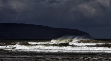 Layers of an incoming tide and storm on the Downhill Beach in th clipart