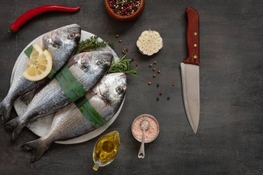 Taze dorado balık, baharat ve zeytinyağı taş kesme tahtası o