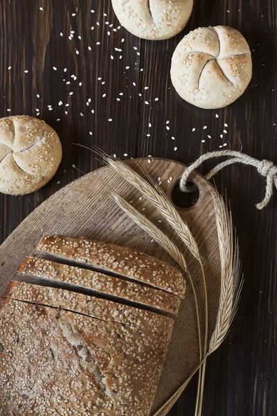 Pan de trigo con sésamo, bollos y espigas de trigo — Foto de Stock