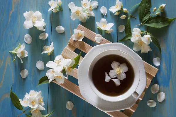 Šálek čaje na dřevěné minipaletě obklopené jasmínovou květinou — Stock fotografie