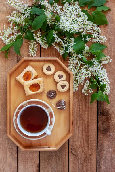 Šálek čaje a různé typy sušenek na dřevěném tácku — Stock fotografie
