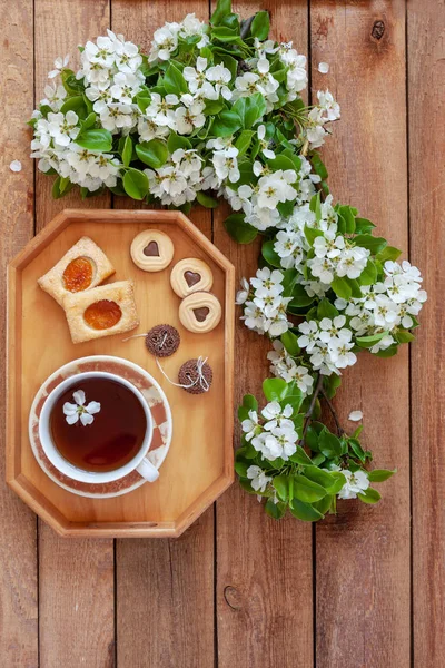 Šálek čaje a různé typy sušenek na dřevěném tácku — Stock fotografie