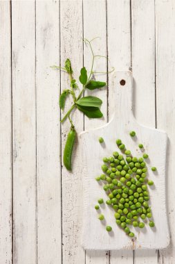 Beyaz ahşap arka plan üzerine yeşil bezelye. Üst görünüm, yakın çekim