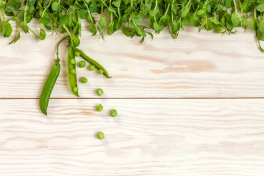 Beyaz ahşap arka plan üzerine yeşil bezelye. Üst görünüm, yakın çekim