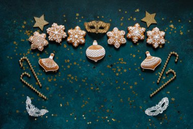 Karlı kurabiyeli zencefilli kurabiye çerçevesi ve koyu yeşil arka planda Noel dekoru.