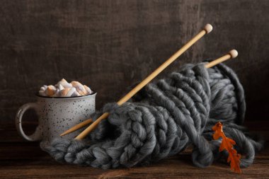 Ahşap örgü iğnelerinde kalın gri ipliklerle örgü örüyorum. 