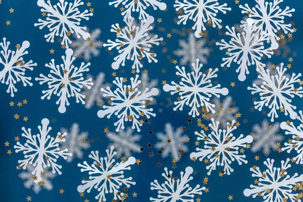 メリークリスマスとハッピーニューイヤーグリーティングカードのデザインは 白い紙で雪の結晶をカットし 青い背景にキラキラのコンフェッティ 季節の休日 バナー ポスター — ストック写真