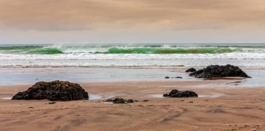 Kuzey İrlanda 'daki County Londonderry' deki Downhill Sahili 'nde gelen gelgit ve büyük taşlardan oluşan bir tepenin üzerinde güzel, bulutlu bir gün batımı. Game of Thrones çekiminin yeri