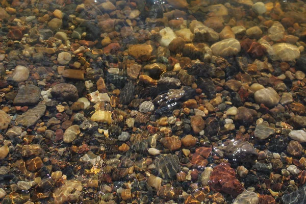 multi-colored stones in clear water /Photo of colored stones in the water.The water is clear, clearly visible bottom of the reservoir in the afternoon in the summer season.It\'s very beautiful.