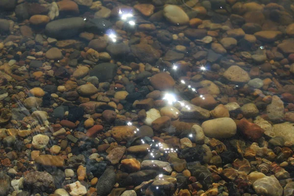 multi-colored stones in clear water /Photo of colored stones in the water.The water is clear, clearly visible bottom of the reservoir in the afternoon in the summer season.It\'s very beautiful.