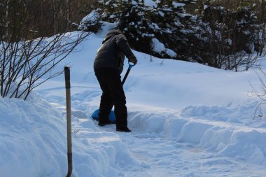 dostum onun ev /There dışında kürek kar beyaz kar soğuk kışın çok. Kırsal kesimde bir adam eve geçiş için kar küreği kaldırır..