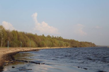 Plajlı beyaz göl ve orman / fotoğraf Beyaz Göl. Büyük mavi dalgalar üzerinde. Kumsal. Dördüncüsü tahta. Ağaçların yeşil yaprakları var. Zaman. Gökyüzü beyaz bulutlarla mavidir. Güneşli bir hava.
