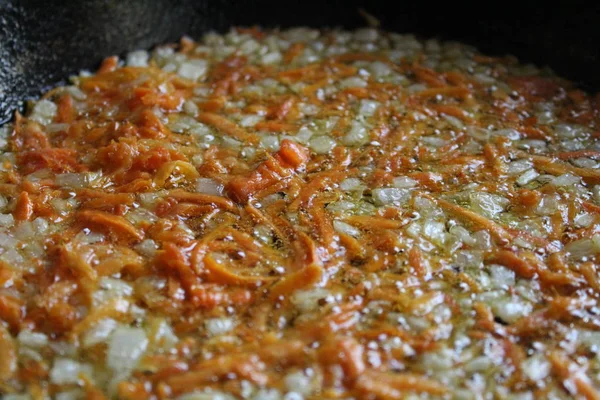 fried onions and carrots in a skillet / photo fried onions and carrots in vegetable oil.cooking in a cast iron skillet at home kitchen.