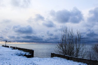 Beyaz Göl 'ün güzel manzarası, Vologda Oblastı, Rusya / güzel bir manzaranın fotoğrafı. Mevsim soğuk sonbahar. Yerde kar ve ağaçlar var. Rıhtım ve yol gölete gidiyor. Gölde küçük dalgalar,