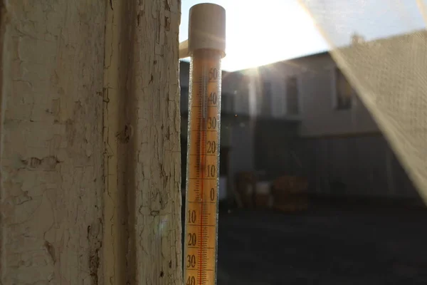 temperature thermometer on the street in the heat of summer / photo of an old street thermometer. the temperature is plus 35 degrees. the air is hot in summer. the glass device hangs outside the window.