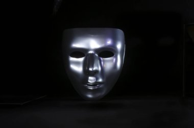 parlak metalik maskeli maske, siyah bir arka plan üzerinde vurgulanır