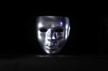 parlak metalik maskeli maske, siyah bir arka plan üzerinde vurgulanır